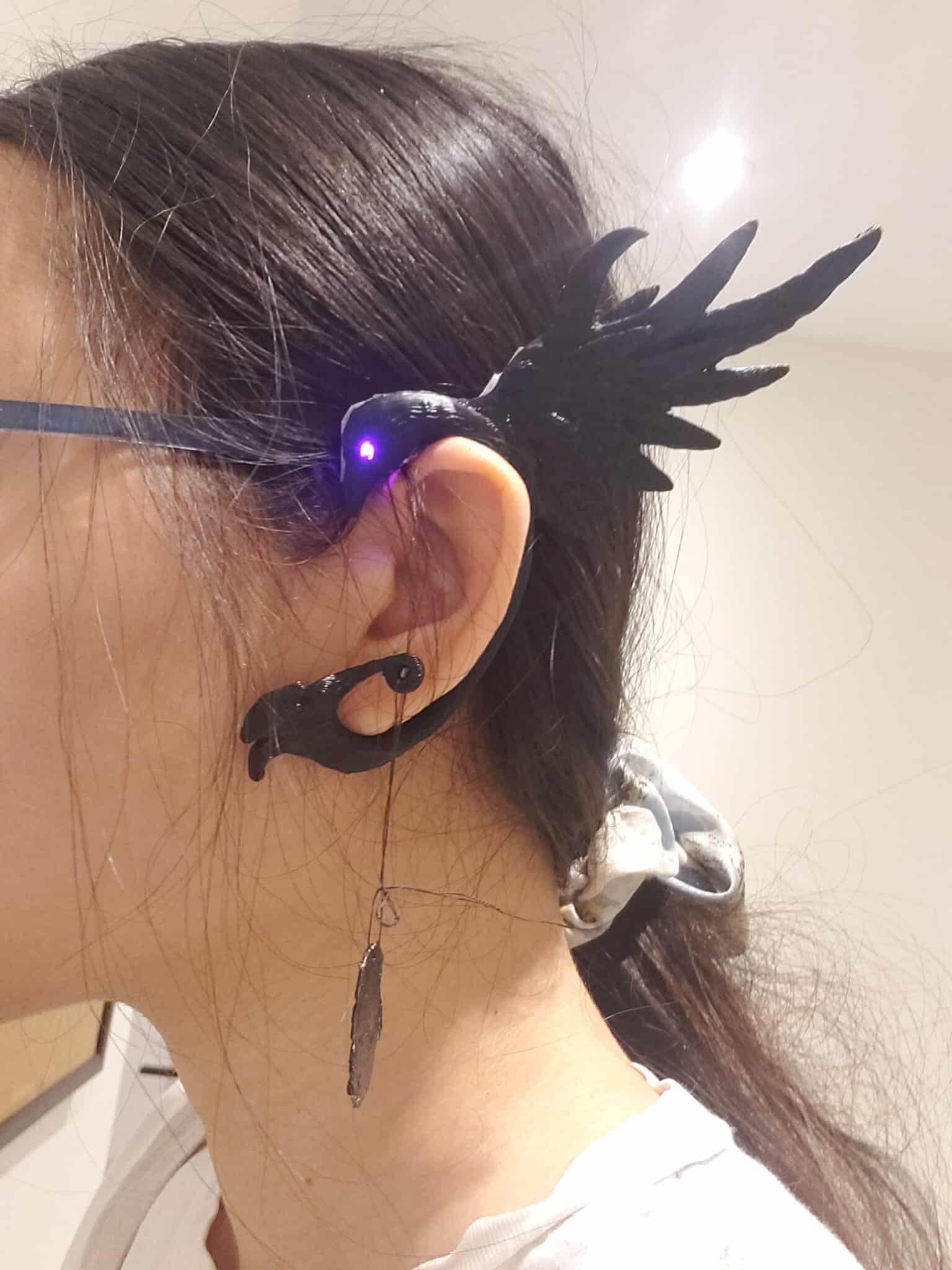 Crow ear cuff when worn. A purple light can be seen coming from the eye